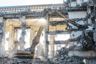 Excavator with long mechanical arm at height breaks off pieces of the house. 