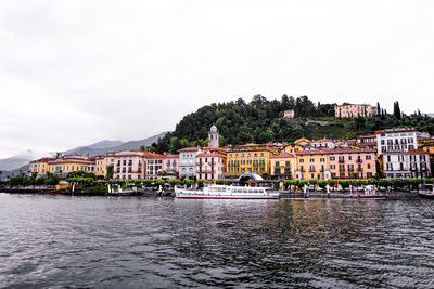 Buildings by river against sky