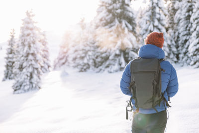 Rear view of woman walking on snow covered field