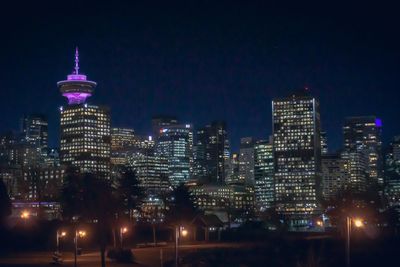 Illuminated buildings in city against sky at night