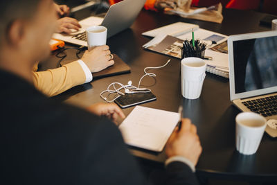 Cropped image of businessman sitting with documents at conference table in office