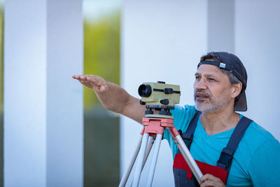 A man works with an optical level to level the landscape.