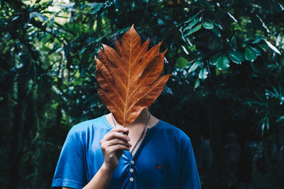 Low section of person holding autumn leaf