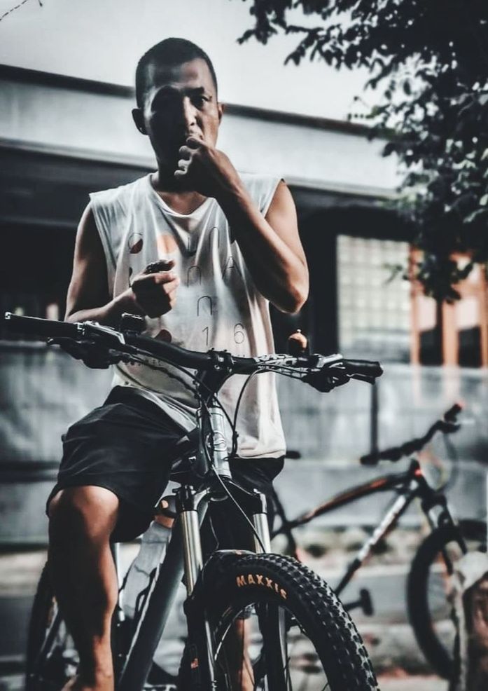 bicycle, sports, adult, transportation, activity, city, cycling, lifestyles, men, one person, architecture, vehicle, young adult, mode of transportation, city life, exercising, motion, street, black, sports equipment, clothing, casual clothing, leisure activity, outdoors, land vehicle, muscular build, vitality, person, wheel, cool attitude, athlete