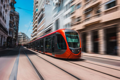 Tramway moving on railroad track against buildings in city