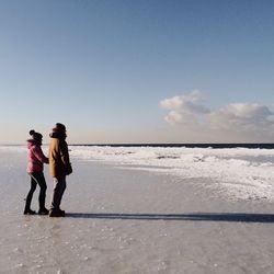 Side view of couple standing on beach