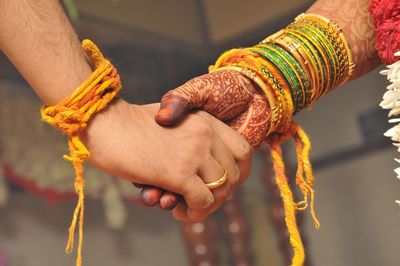Cropped image of couple holding hands during wedding ceremony