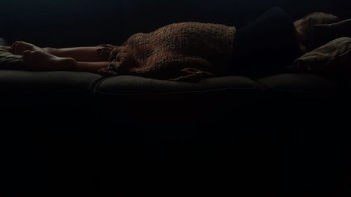 Close-up of man lying down against black background