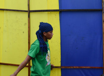 Young woman standing against yellow wall