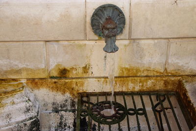 Close-up of old fountain against wall