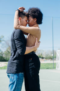 Young couple embracing each other standing at sports court