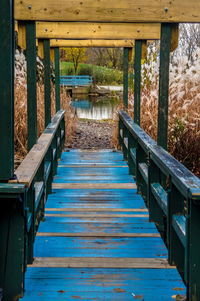 Old blue footbridge leading towards pond