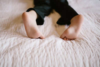 Low section of boy relaxing on bed at home