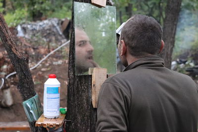 Man looking into mirror at forest