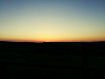 Scenic view of silhouette field against clear sky during sunset