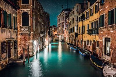 Canal amidst buildings in city at night