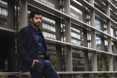 Young man looking away while standing on railing