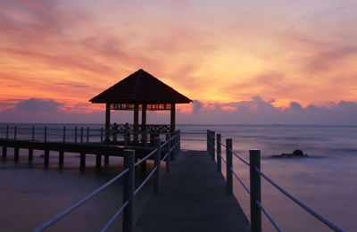 Pier over sea against sky during sunset