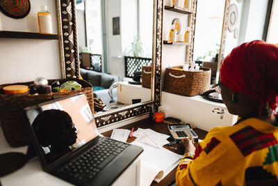 Female hairdresser with laptop at table in barber shop