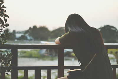 Rear view of woman standing by railing against sky