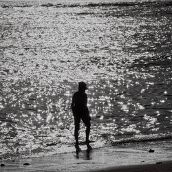 Rear view of silhouette man standing on beach