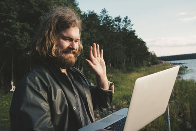 Smiling man doing video call on laptop against forest