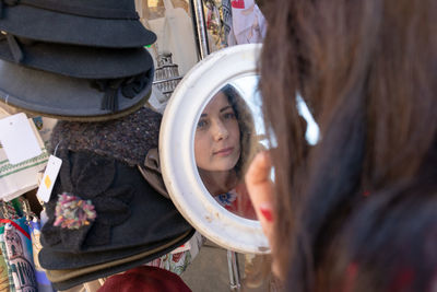 Close-up of woman looking at mirror with reflection at market