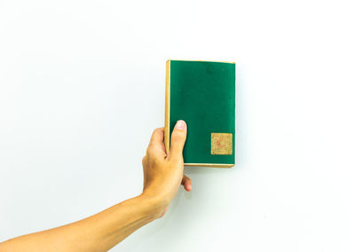 Close-up of hand holding paper against white background