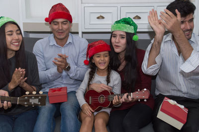 Cute girl playing guitar with family at home