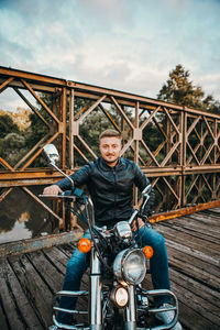 Portrait of man sitting on bridge