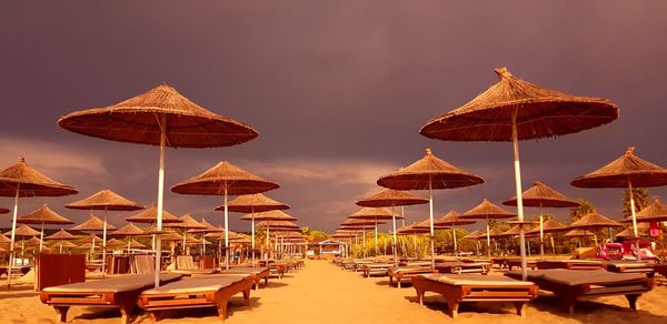 Lounge chairs and umbrellas on beach against sky