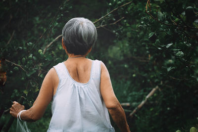 Rear view of woman standing against trees