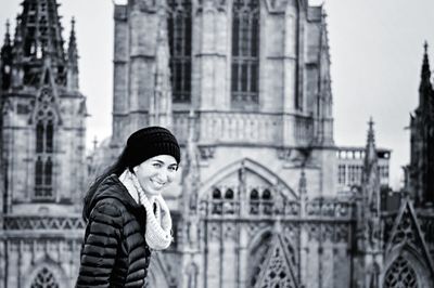 Portrait of smiling woman by church in city during winter