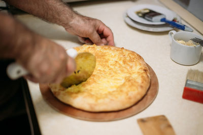 Close-up of man cutting pie at table