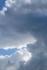 Low angle view of sunlight streaming through clouds