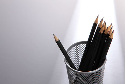 High angle view of pencils in container against gray background