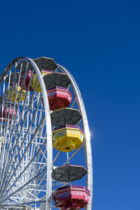 Low angle view of ferris wheel against clear blue sky