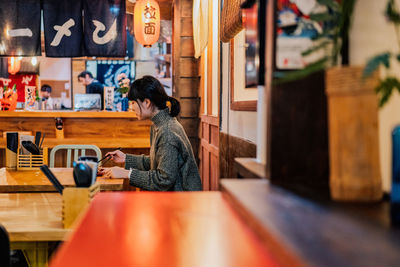 Side view of woman sitting on table in cafe