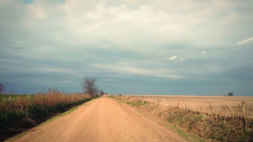 Road amidst field against sky