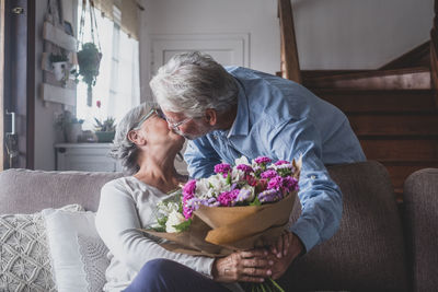 Senior couple kissing while holding flower bouquet