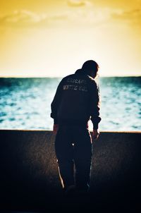 Rear view of man looking at sea against sky