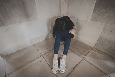 Full length of sad woman sitting on floor