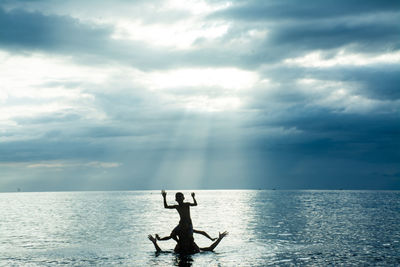 Silhouette people on sea against sky