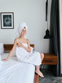 Portrait of young woman standing against curtain