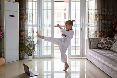 Full length of girl practicing taekwondo at home