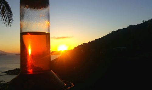 Close-up of beer in sea against sky during sunset