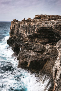 Rock formation in sea against sky