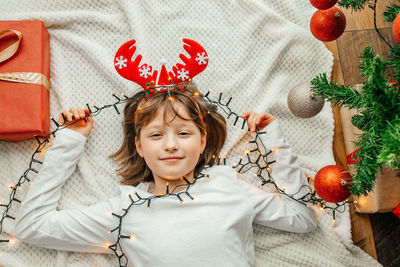 A happy girl lies on a white plaid next to the christmas tree in new year's decorations