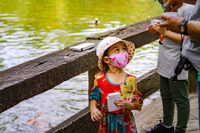 Fancy little girl wearing face mask at the lake.