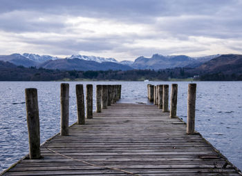 Wooden pier over lake against mountains